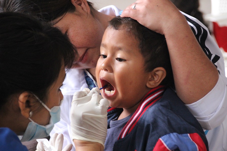Two dental team members examining child's smile