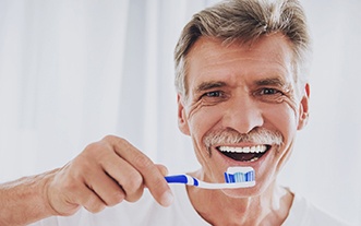 man enjoying the day-to-day benefits of dental implants through brushing
