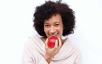 Woman with dental implants in Glastonbury eating an apple