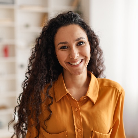 Woman in orange shirt smiling at home