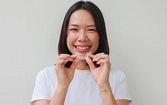 Woman smiling while holding clear aligner