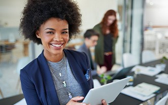 Woman smiling while holding laptop at work