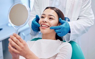 Woman smiling at reflection in handheld mirror